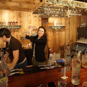 Two women working behind a bar counter, serving drinks and attending to customers.