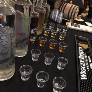 multiple bottles of wiggly bridge spirits poured into mini tester cups on a table during a taste testing event held at the barn