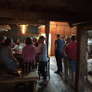 people sitting at a bar in the wiggly bridge barn and some people conversing and standing