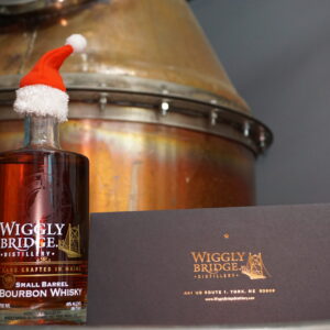 a bottle of wiggly bridge bourbon whiskey wearing a little santa hat next to a gift certificate