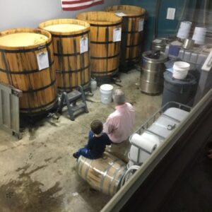 a photo of a man and his grandson sitting on barrels, conversing
